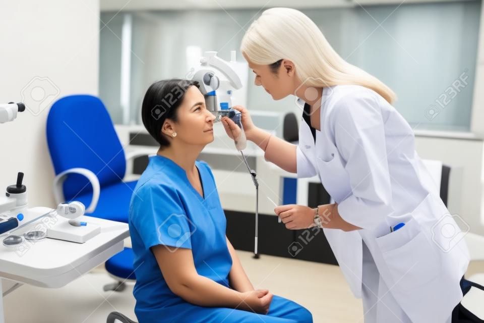 Vrouwelijke oogarts meten van de oogdruk met moderne tonometer aan een senior patiënt in het medisch kantoor