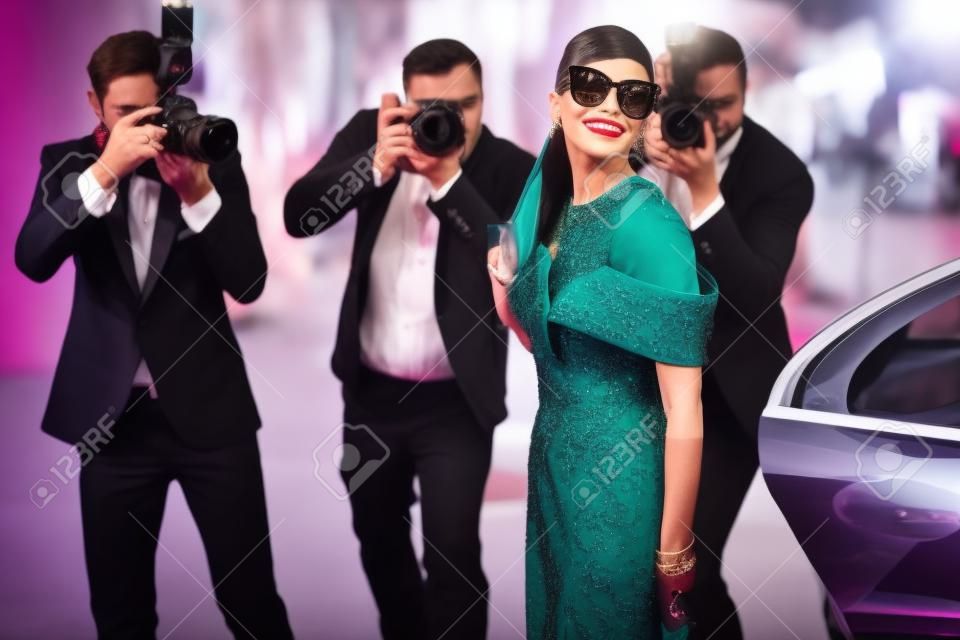 Bella donna vestita in stile retrò come una famosa attrice cinematografica che arriva alla cerimonia di premiazione con i fotoreporter che la fotografano