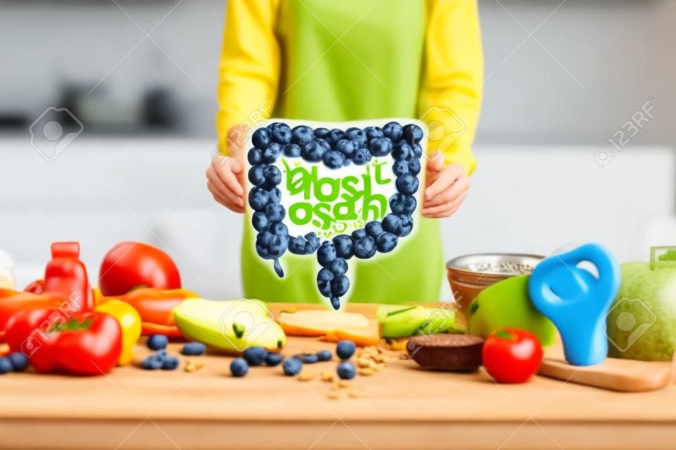 Holding bowel model with variety of healthy fresh food on the table. Concept of balanced nutrition for gut health