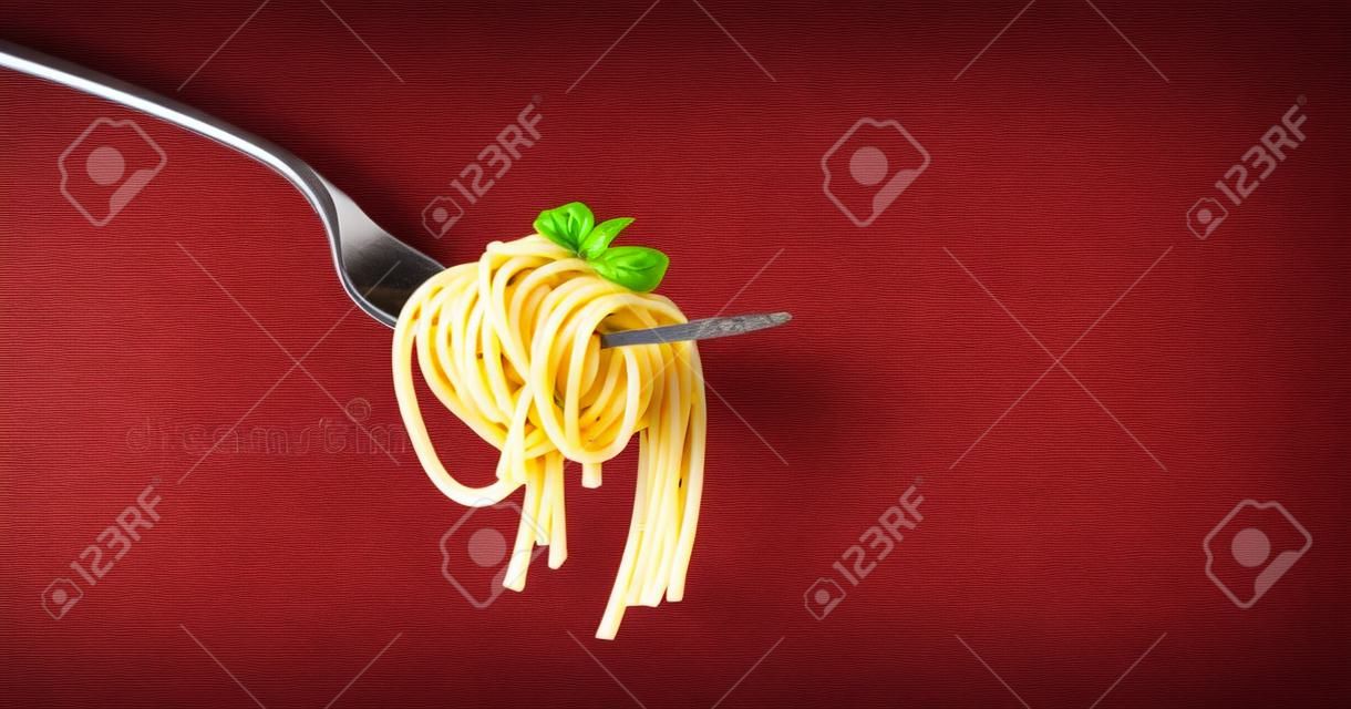 Pasta de espaguetis con tomate y albahaca en la horquilla. Comida italiana. Espacio para texto. Imagen de estudio profesional