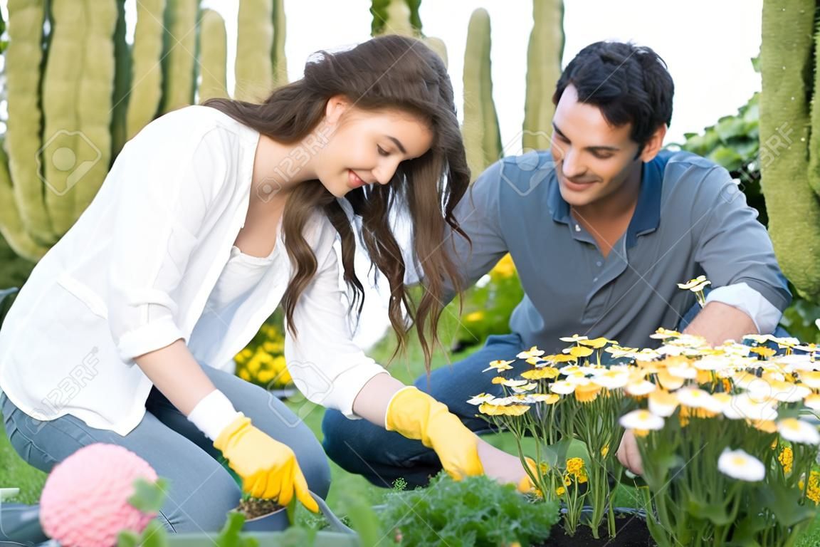 행복한 젊은 부부는 그들의 정원에 식물 야외 돌보는의 초상화