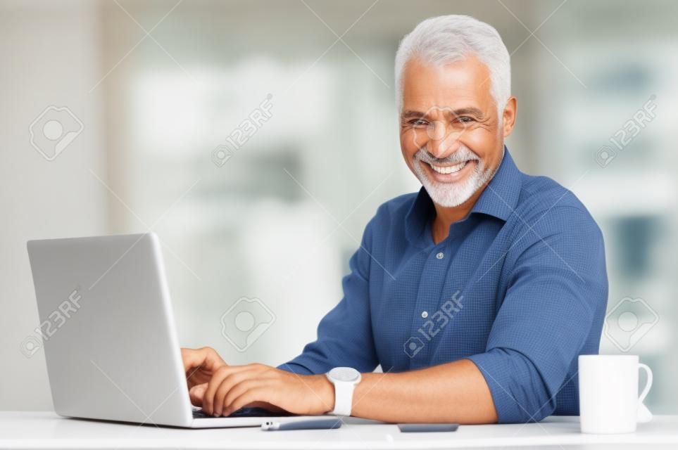Portrait d'un sourire homme d'âge mûr Utiliser un ordinateur portable Heureux Au Bureau