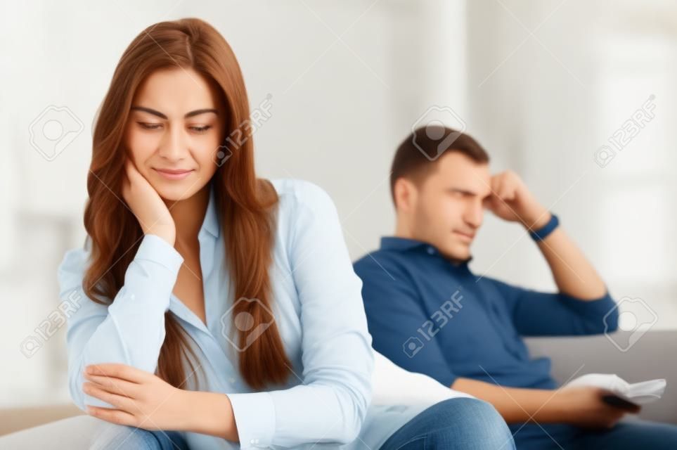 Triste pareja sentada en el sofá después de haber pelea