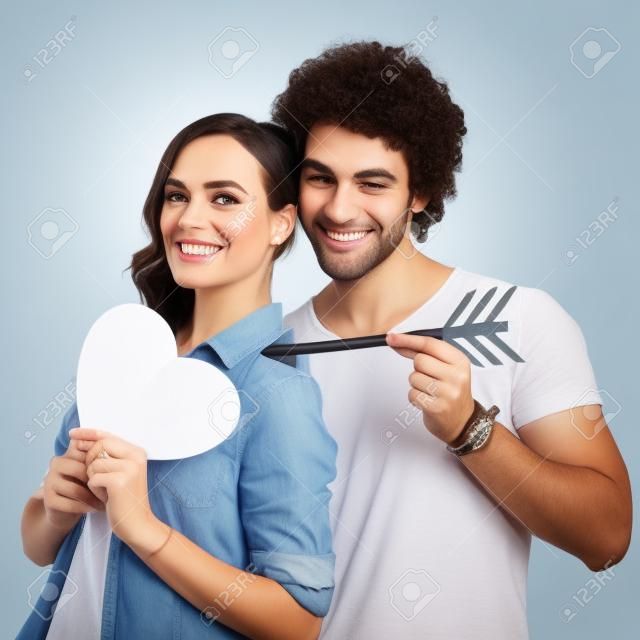 快乐的夫妇抱着箭与纸心孤立的白色背景