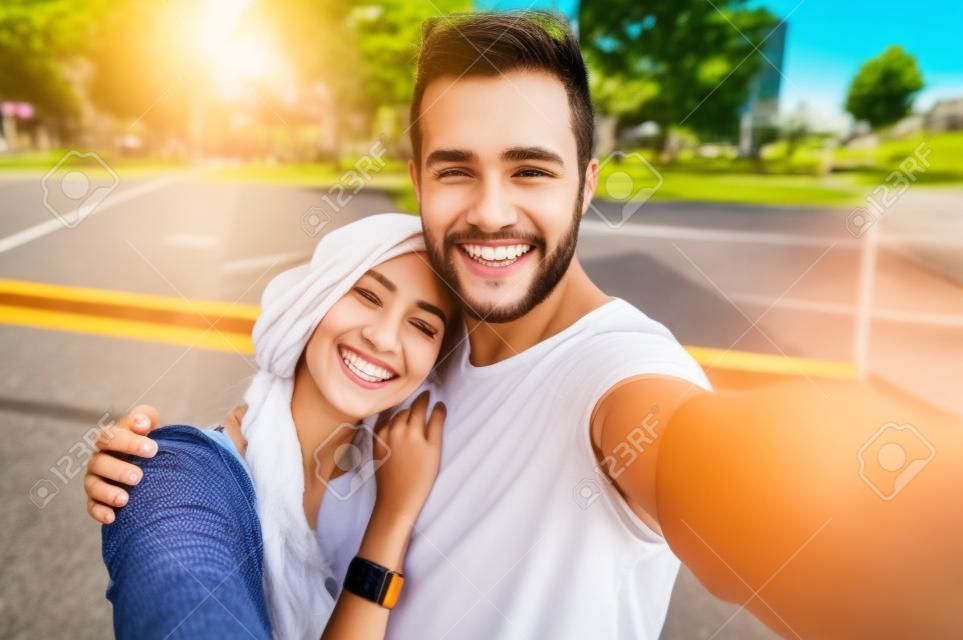 Gros plan d'un jeune couple de prendre extérieure selfie. Jeune homme de prendre une photo avec sa petite amie. Happpy couple souriant prenant un selfie dans un jour d'été.
