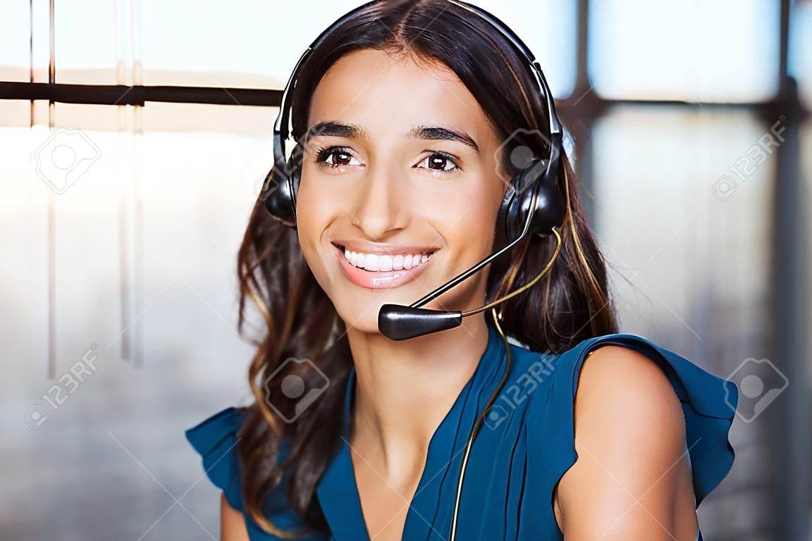Mujer de soporte al cliente sonriendo y mirando a cámara. Retrato de operador de telefonía de soporte al cliente feliz en el centro de llamadas con auriculares. Ejecutivo alegre a su servicio trabajando en oficina.