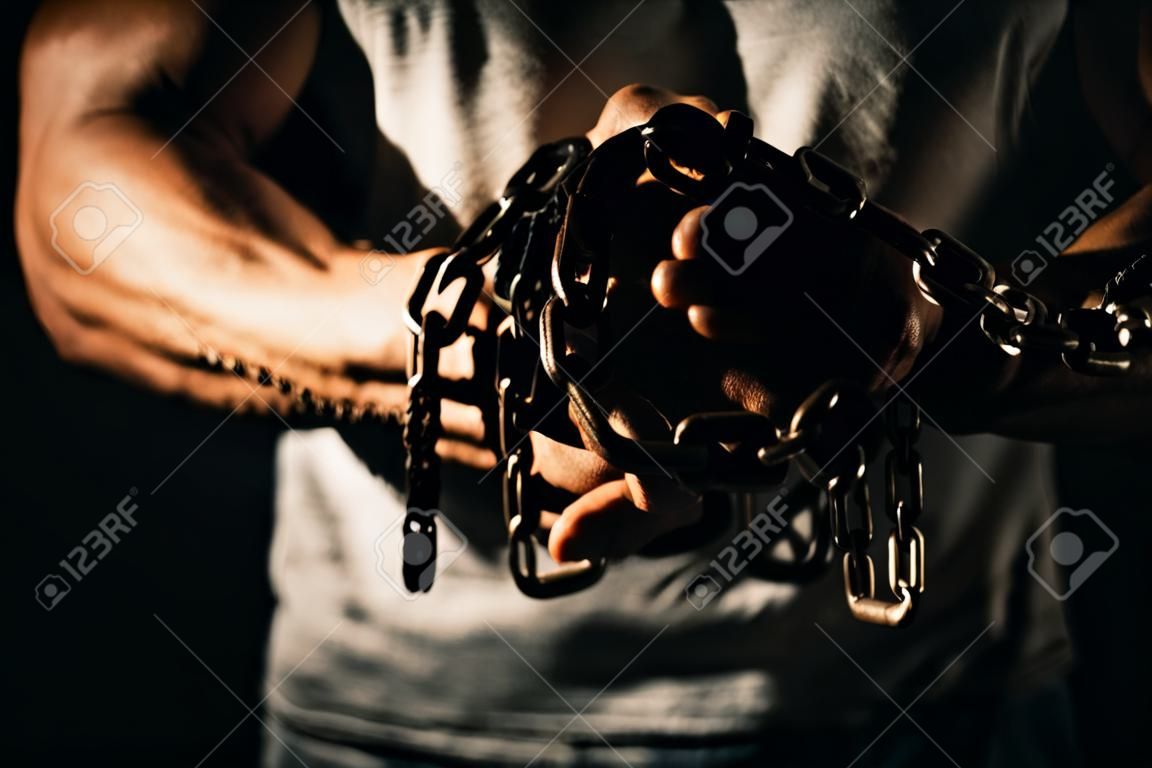 Midsection of muscular man holding chain against black background