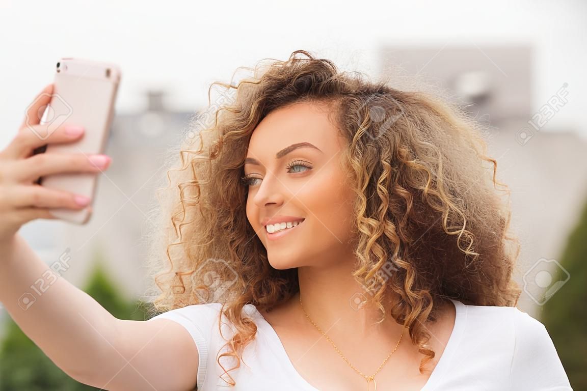 Beautiful curly hair girl taking selfie