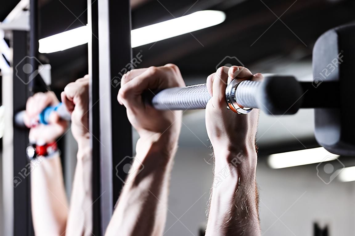 Closeup detail of male hands holding a pull-ups bar in a gym