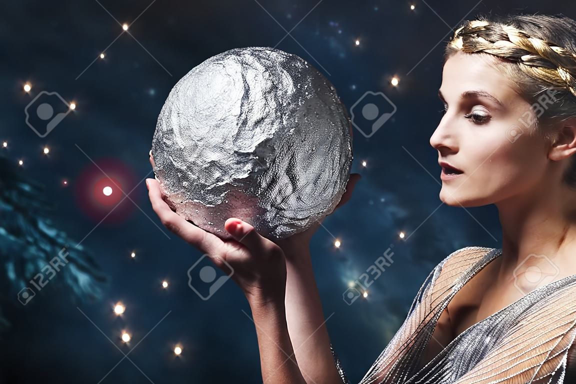 Kobieta trzyma srebrną kulę na tle rozgwieżdżonego nieba