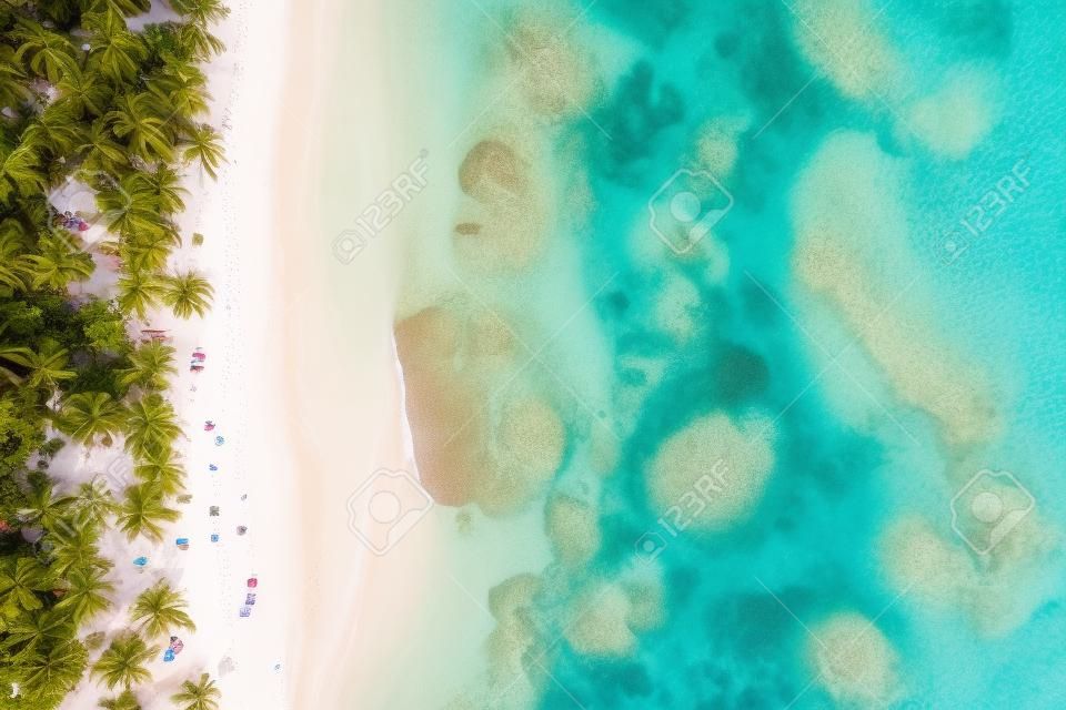Drone shot of tropical beach with white boat anchored.Samana peninsula,Grand Bahia Principe El Portillo beach,Dominican Republic.
