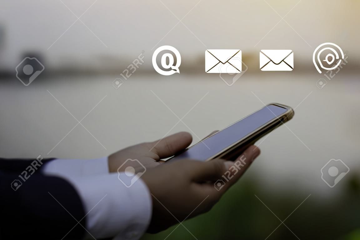 Skontaktuj się z nami lub skontaktuj się z infolinią obsługi klienta. biznesmen za pomocą telefonu komórkowego z ikonami (e-mail, telefon, poczta).