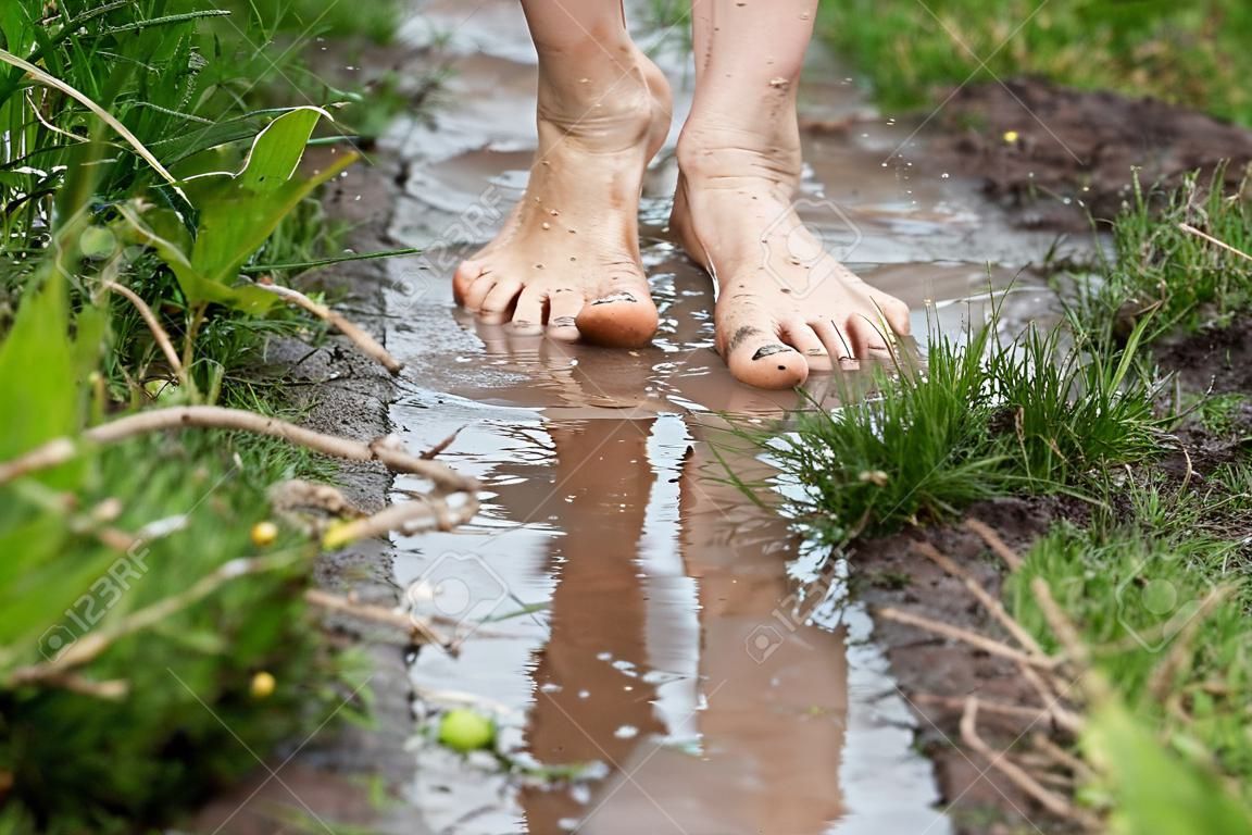 맨발로 웅덩이를 걷는 젊은 여성의 발