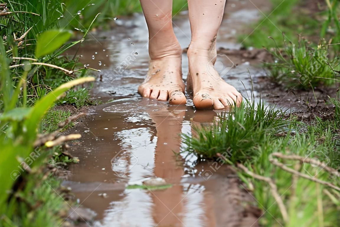 맨발로 웅덩이를 걷는 젊은 여성의 발