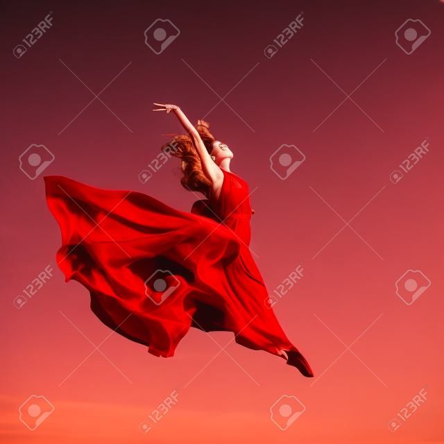 Donna in aria abito rosso che salta in aria