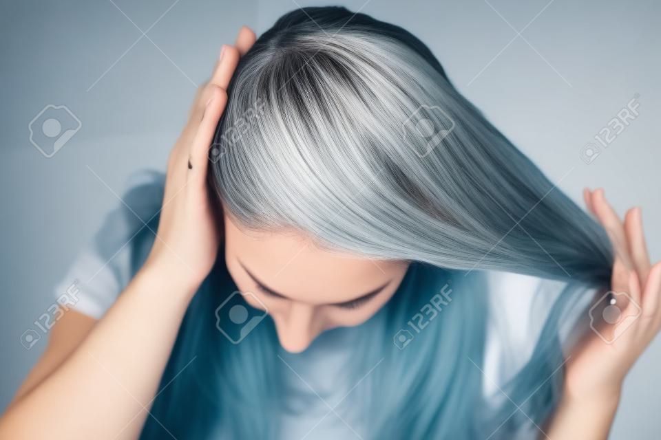 Nahaufnahme des Kopfes einer Frau mit geteilten grauen Haaren, die aufgrund der Quarantäne nachgewachsen sind.