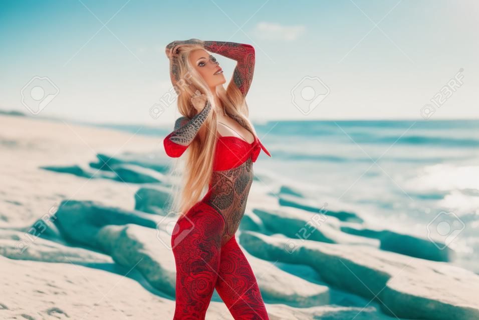 Une Femme En Maillot De Bain Rouge Se Dresse Sur Le Sable.