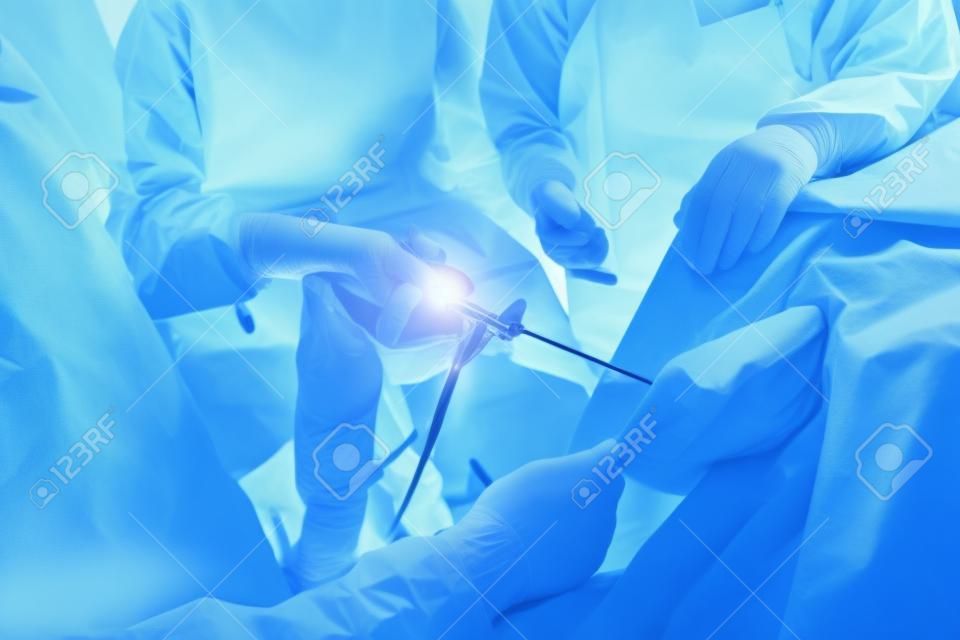 Chirurdzy ortopedzi zajmujący się chirurgią artroskopową w pracy zespołowej na sali operacyjnej z nowoczesnymi narzędziami artroskopowymi chirurgii kolana w tle szpitala