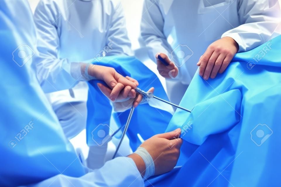 Chirurdzy ortopedzi zajmujący się chirurgią artroskopową w pracy zespołowej na sali operacyjnej z nowoczesnymi narzędziami artroskopowymi chirurgii kolana w tle szpitala
