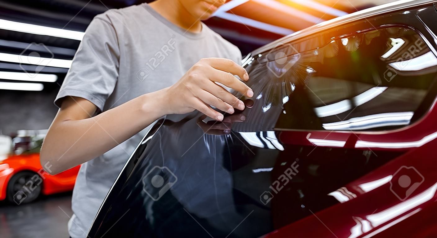 Applying tinting foil on a car window in a auto service