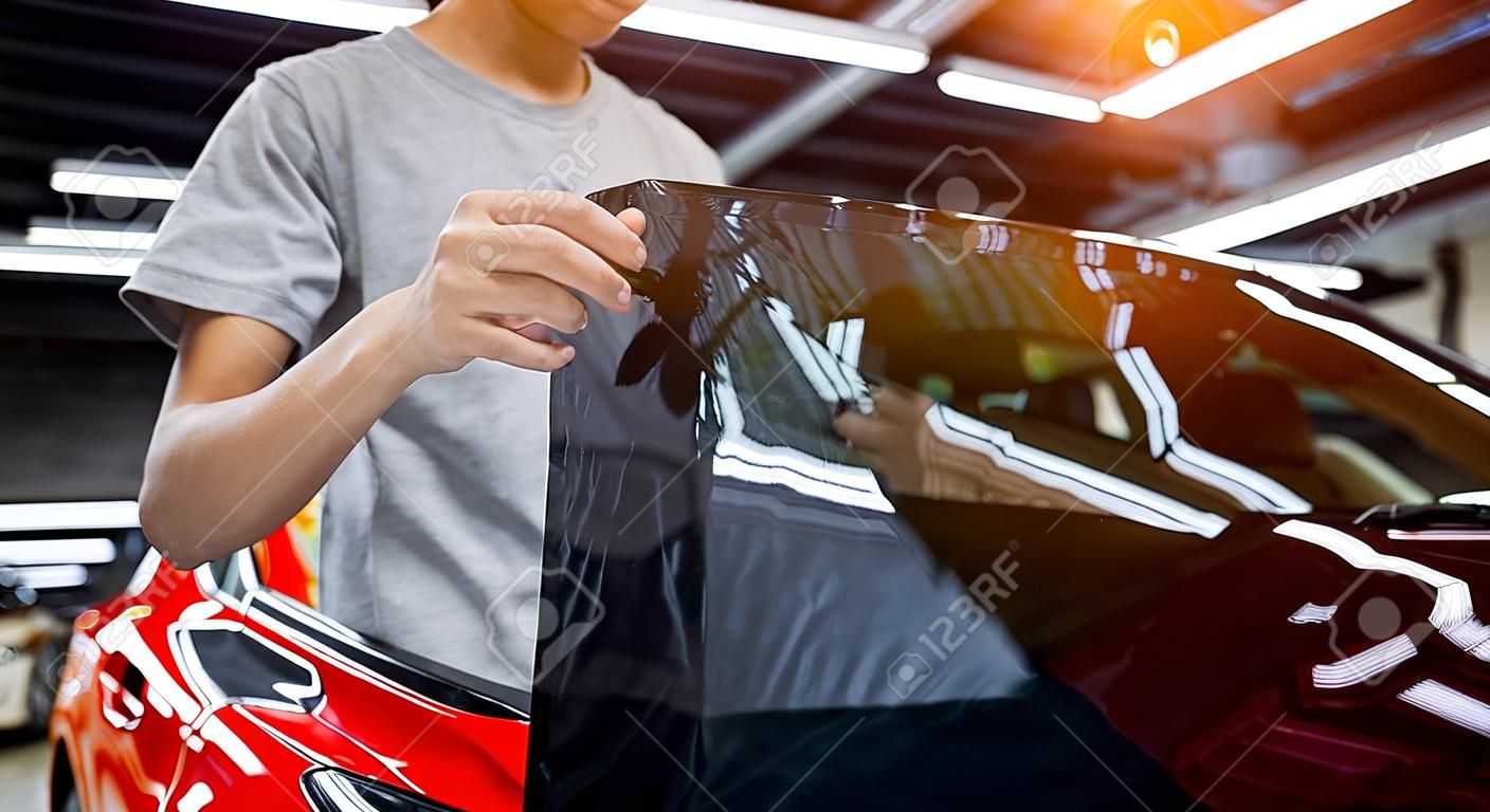 Applying tinting foil on a car window in a auto service