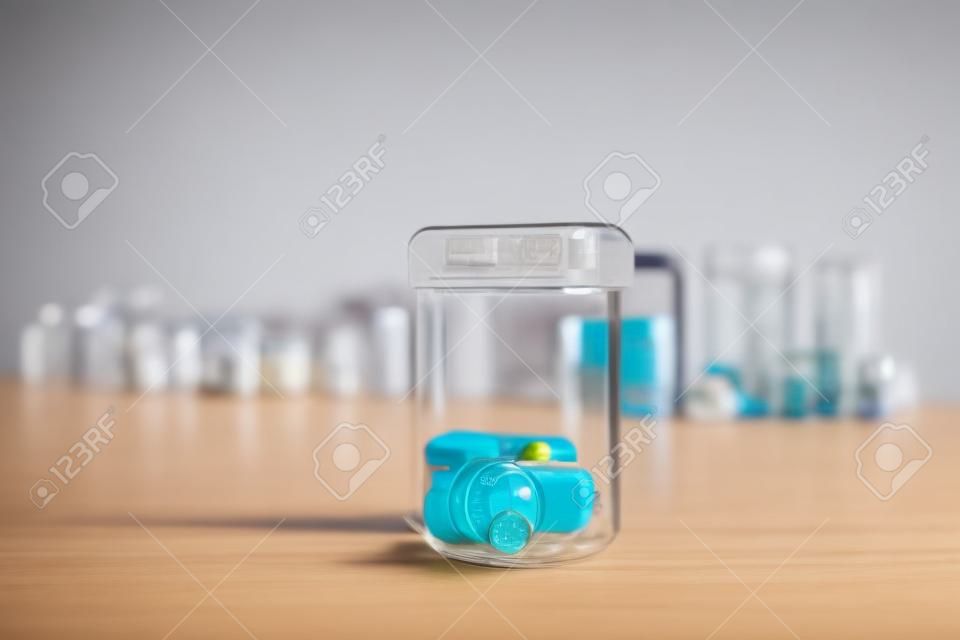 Measuring cylinder with drugs on table. Medical vials in the background.