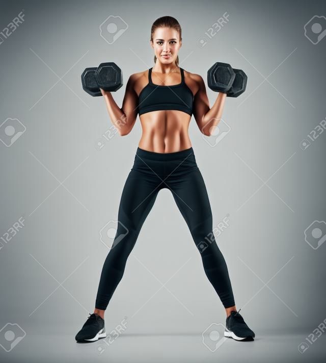 Güzel genç kadin, egzersiz, pompalama, yukarı, kaslar, sırt, eller, dumbbells. Fotoğraf atletik kadın, mükemmel vücut, beyaz zemin üzerine izole edilmiştir. Güç ve motivasyon