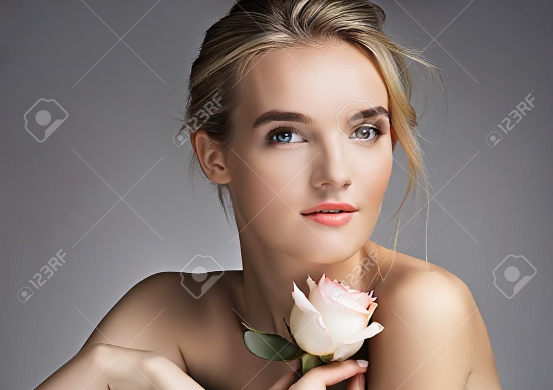 有自然的美麗的小姐組成。金發女孩與玫瑰在灰色的背景上的照片。護膚概念