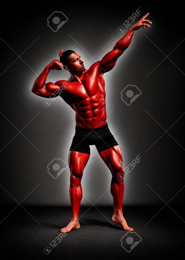 Athletischer Mann, der aufwirft. Foto des Mannes mit perfektem Körperbau auf schwarzem Hintergrund. Kraft und Motivation