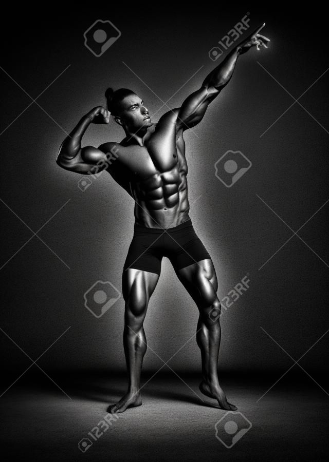 Athletischer Mann, der aufwirft. Foto des Mannes mit perfektem Körperbau auf schwarzem Hintergrund. Kraft und Motivation