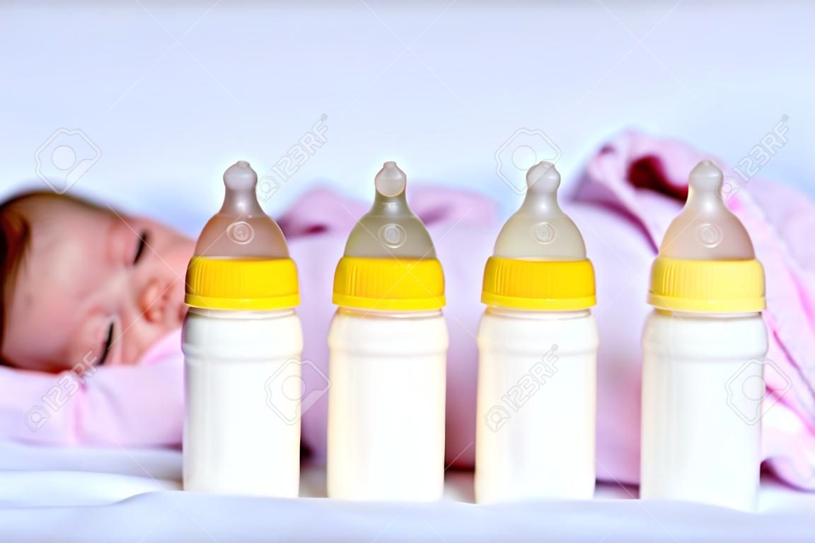 Crying newborn baby girl with nursing bottles. Bottle feeding