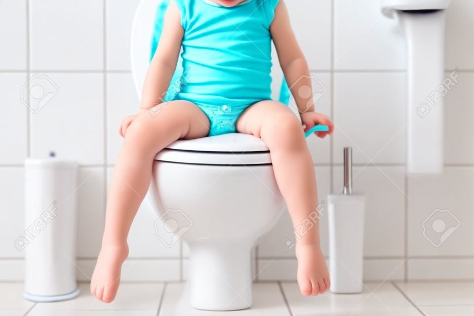 トイレのトイレの座席に座ってかわいい幼児の女の子の子供のクローズアップ。小さな子供のためのトイレトレーニング。子供の認識できない顔