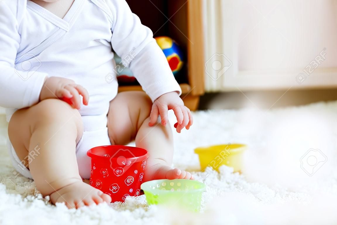 Primo piano del piccolo bambino sveglio della neonata del bambino che si siede sul vasino. Bambino che gioca con il giocattolo educativo e il concetto di addestramento della toilette. Apprendimento del bambino, fasi di sviluppo. Nessuna faccia, persona irriconoscibile.