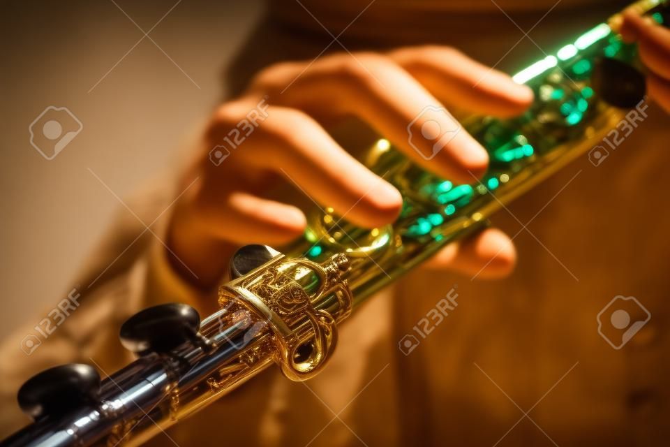 Shallow depth of field. Part of a flute with the right hand of a man on a flute close-up. Musical theme. Wind instrument. Modeling light.