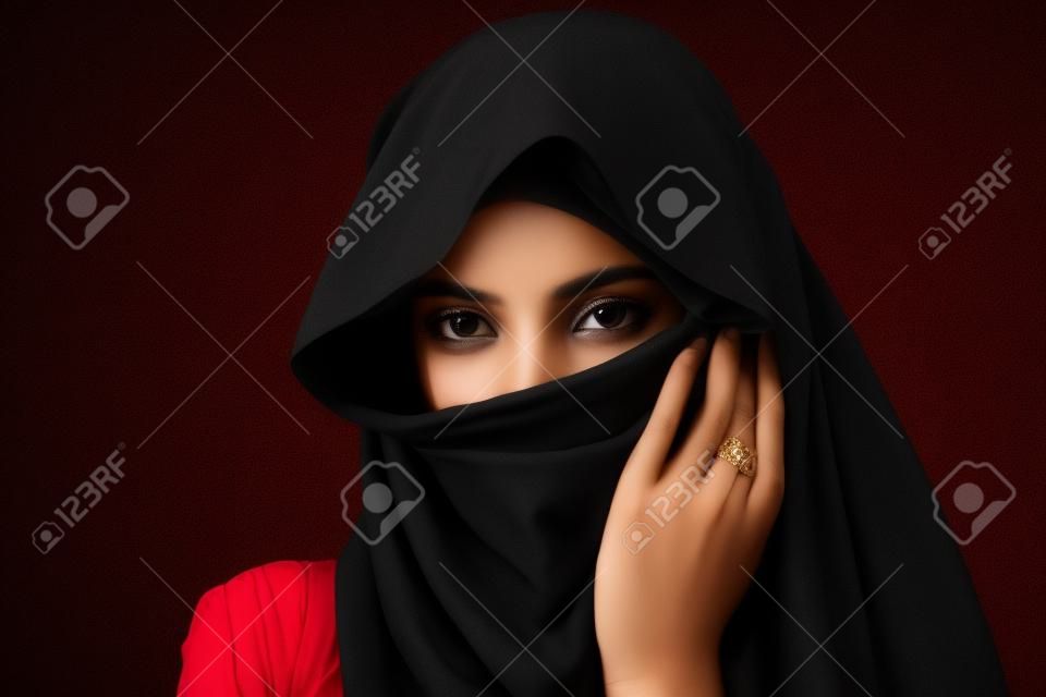 Portrait of young muslim woman on a black background.
