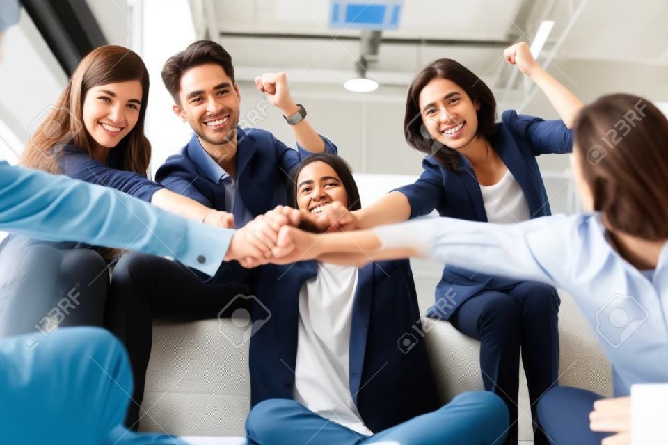 Young successful businesspeople are fist bumping after working hard at new project