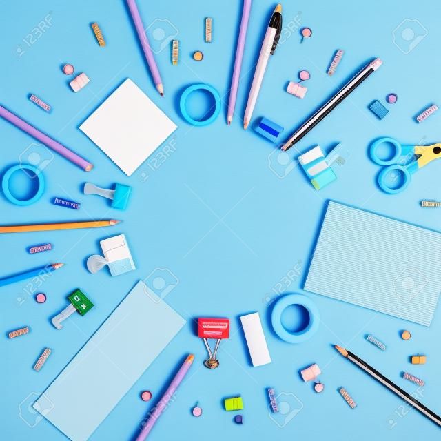Runder Rahmen aus Schulmaterial auf blauem Pastellgrund. Einfarbiges kreatives Konzept mit Kopienraum.