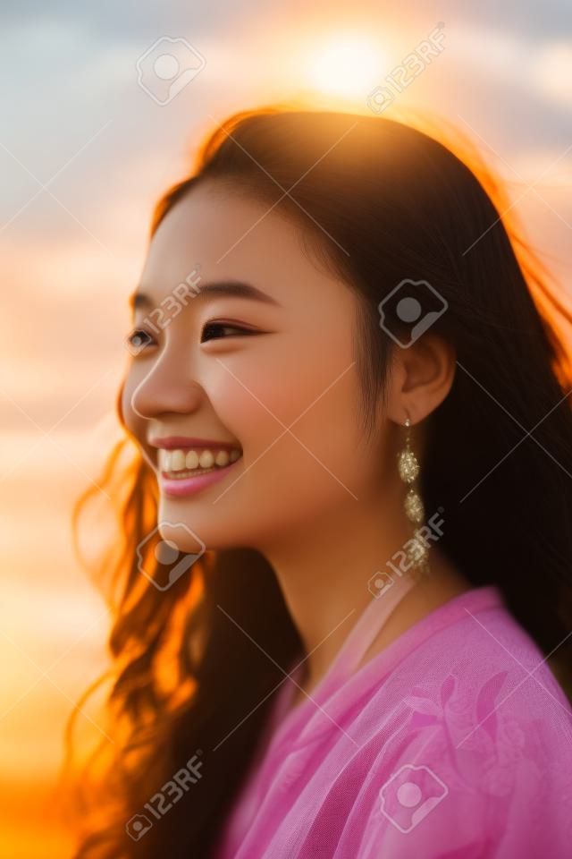 Portrait d'une belle jeune femme asiatique souriante au coucher du soleil.