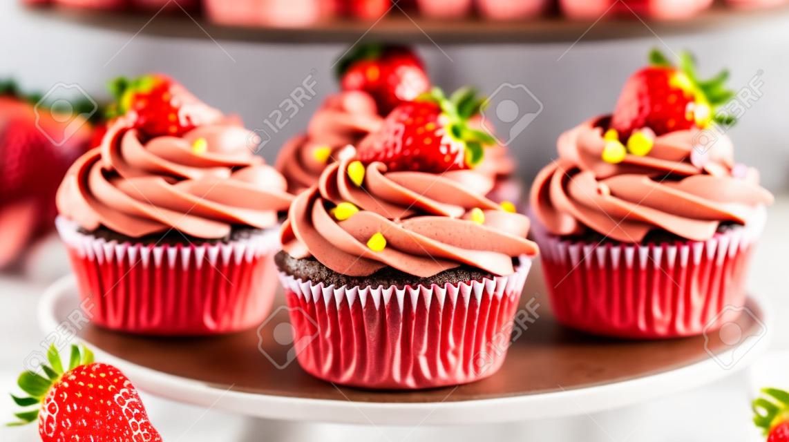 Strawberry cupcakes with chocolate frosting and fresh strawberries.