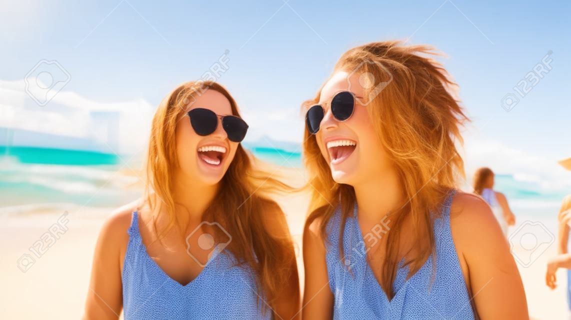 Porträt zweier glücklicher junger Frauen, die Spaß am Strand haben.