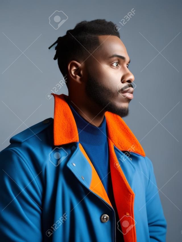 Hübscher afroamerikanischer mann in orangefarbener jacke auf blauem hintergrund