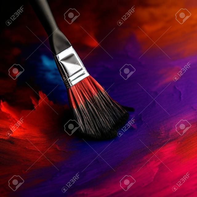 Paint brush and palette of colors on a dark background closeup