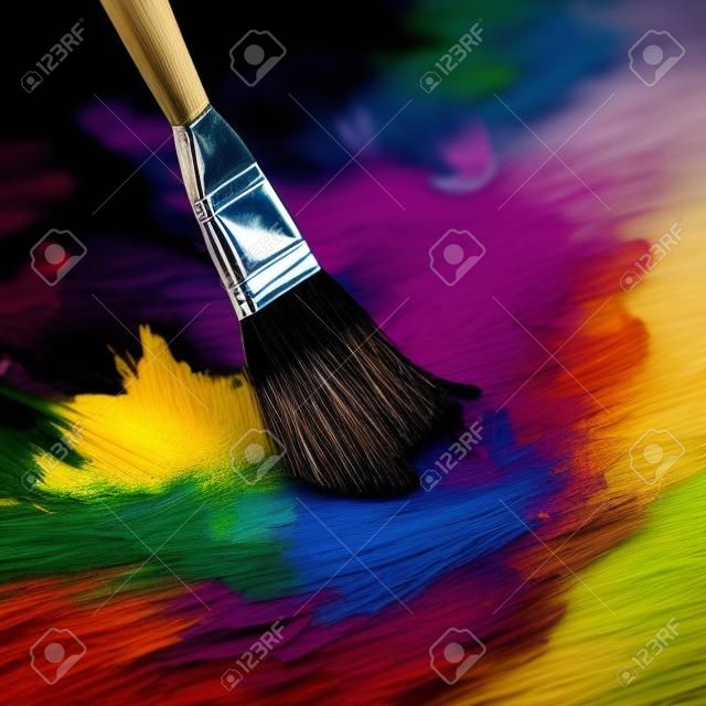 Paint brush and palette of colors on a dark background closeup