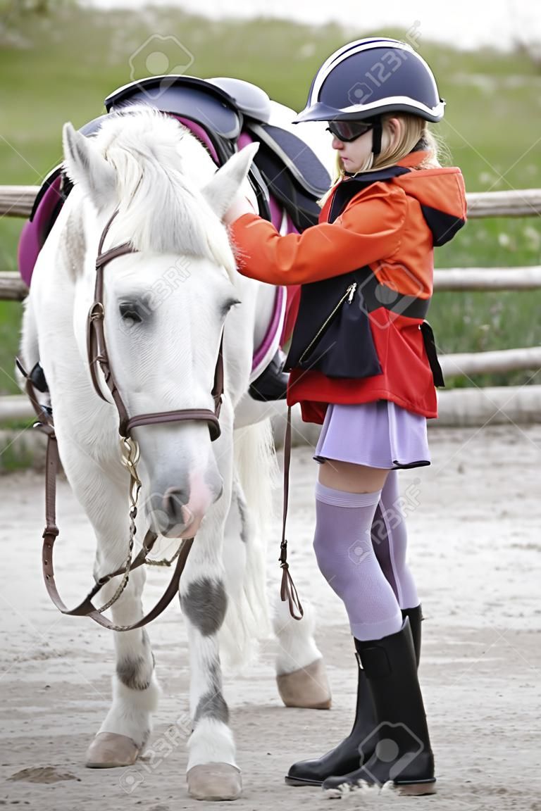 young girl with white little horse outdoors