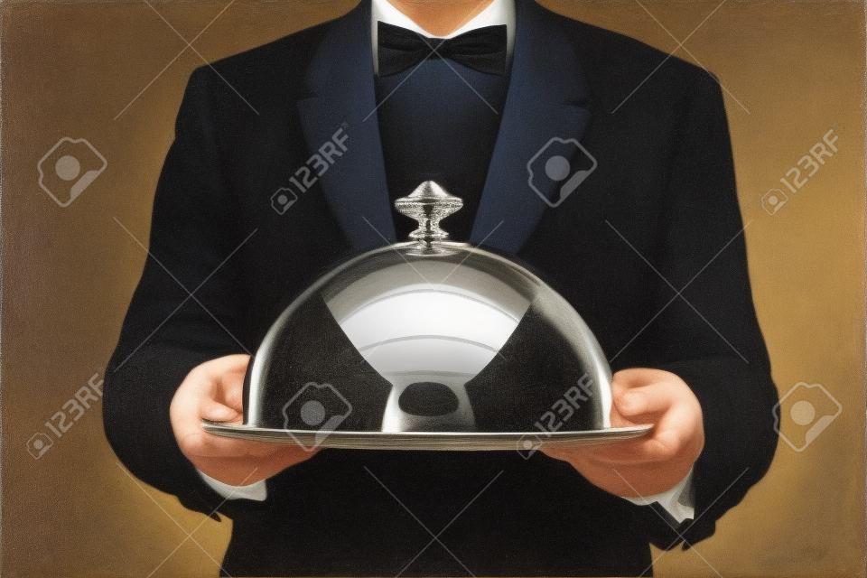 Официант, обслуживающий едой под серебро колокол или купол