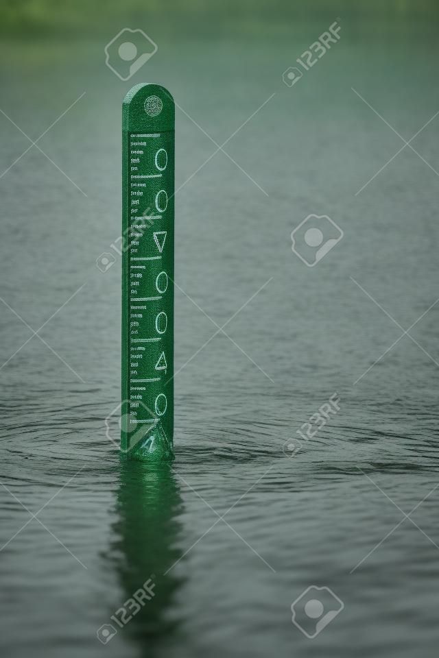 Flood level diepte marker post met regen vallen in het omringende water