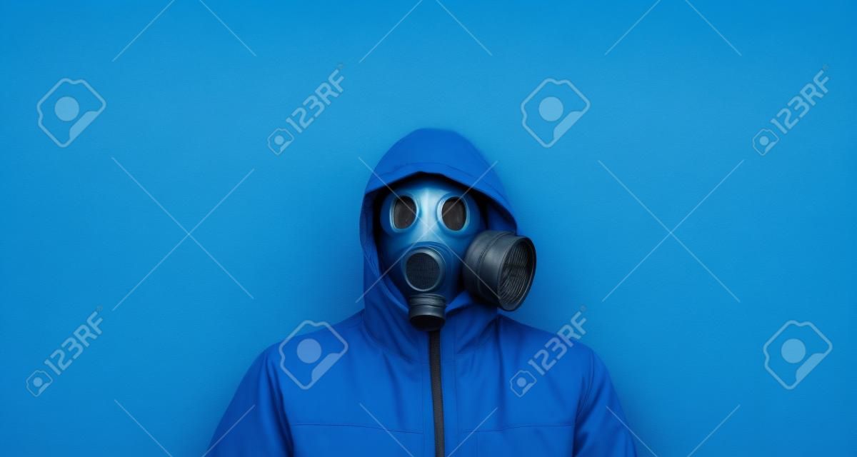 Mężczyzna w masce gazowej i kapturze na niebieskim tle