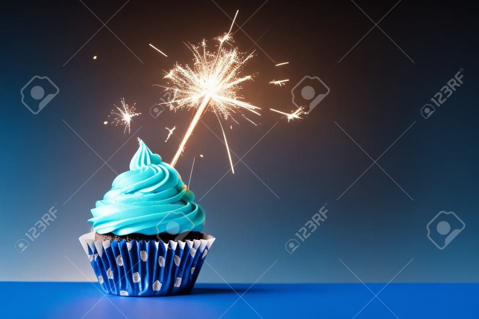 Cupcake mit Wunderkerze gegen blauen