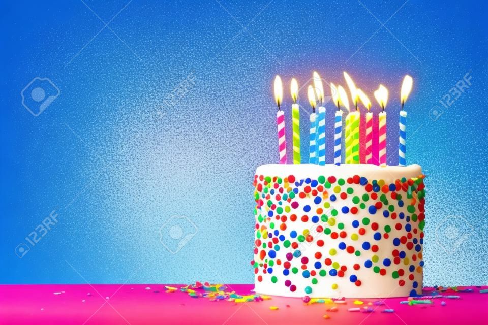 Pastel de cumpleaños colorido con chispitas y diez velas sobre un fondo azul con copyspace