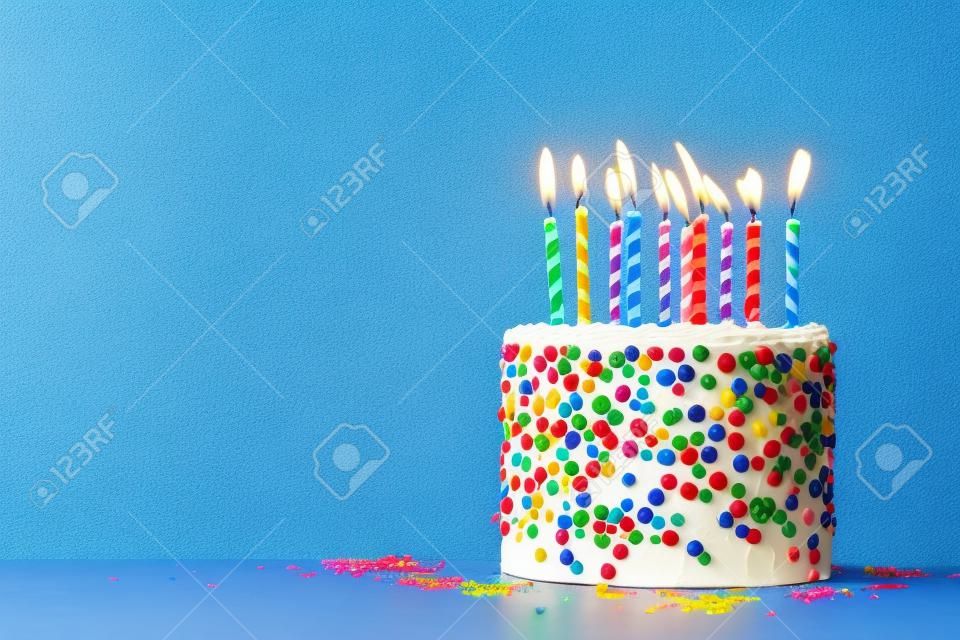 Bolo de aniversário colorido com aspersores e dez velas em um fundo azul com copyspace